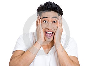 portrait of a happy young handsome man looking shocked surprised in full disbelief hands on cheek open mouth eyes, isolated on