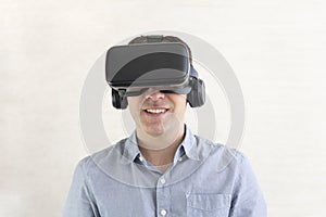 Portrait of happy young handsome man, positive smiling guy using, wearing a modern device virtual reality headset mask