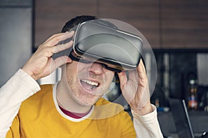 Portrait of happy young handsome man, positive smiling guy using, wearing a modern device virtual reality headset mask