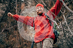 Portrait of happy young hiker man hiking in mountains wearing red clothes exploring new place.