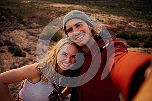 Portrait of happy young hiking couple taking selfie from top of the mountain