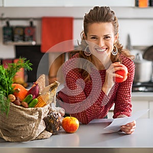 Portrait of happy housewife holding grocery shopping check