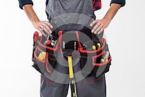 Portrait of happy young indian male construction worker with tool belt isolated on white background