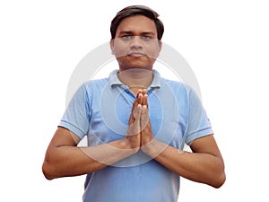 Portrait of a happy young Indian man welcoming people by putting palms together in namaste gesture and greetings