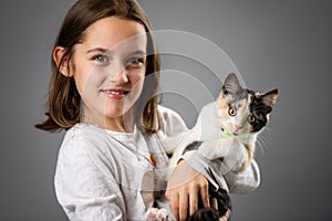 Portrait of happy young little girl with calico kitten cat