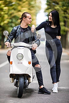 Portrait of happy young love couple on scooter enjoying themselves in a park at summer time