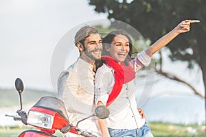 Portrait of happy young love couple on scooter enjoying themselves in a park at summer time