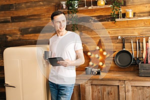 Portrait of happy young man in casual clothes using digital tablet.