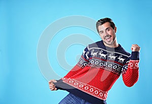 Portrait of happy young man in Christmas sweater on blue background