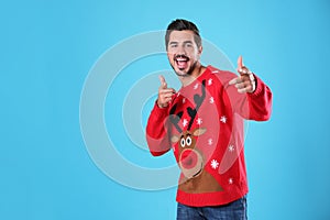 Portrait of happy young man in Christmas sweater on light blue