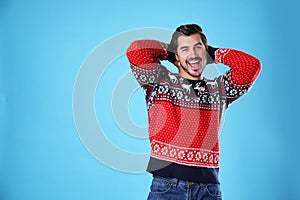 Portrait of happy young man in Christmas sweater on light blue background
