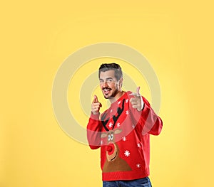 Portrait of happy young man in Christmas sweater on yellow