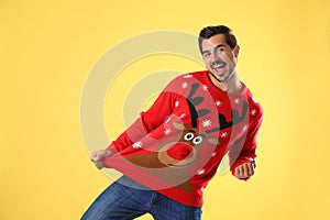 Portrait of happy young man in Christmas sweater on yellow