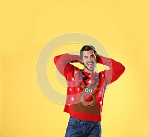 Portrait of happy young man in Christmas sweater on yellow