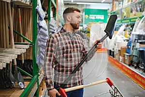 Portrait of a happy young man and customer buying a shovel while shopping at the hardware store