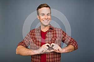 Portrait of happy young man making heart with fingers