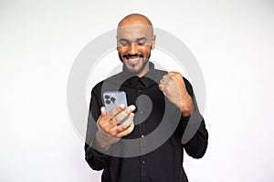 Portrait of happy young man with phone making winning gesture