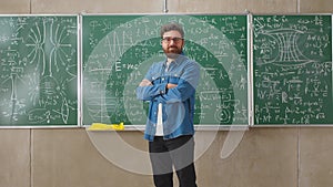 Portrait of happy young man student standing in class with arms crossed smiling looking at camera