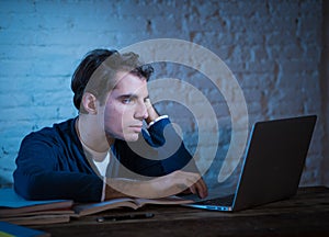 Portrait of a happy young man studying working on laptop late at night