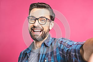 Portrait of a happy young man taking a selfie photo isolated over pink background. Close-up