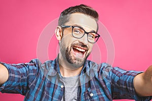 Portrait of a happy young man taking a selfie photo isolated over pink background. Close-up