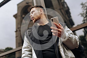 Portrait of happy young man walking on the street and looking aside while talking by his phone