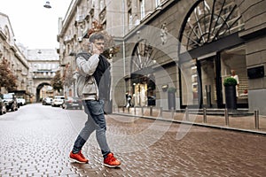 Portrait of happy young man walking on the street and looking aside while talking by his phone