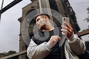 Portrait of happy young man walking on the street and looking aside while talking by his phone