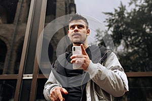 Portrait of happy young man walking on the street and looking aside while talking by his phone