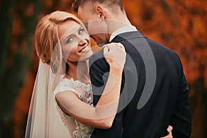 Portrait of Happy young married couple in golden yellow fall autumn park. beautiful bride and stylish groom hugging in