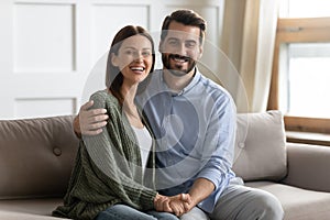 Portrait of happy young married couple sitting on sofa.