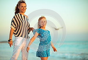 Portrait of happy young mother and child on beach in evening