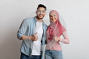 Portrait of happy young muslim couple gesturing thumbs up at camera