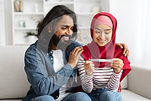 Portrait Of Happy Young Muslim Couple Looking At Positive Pregnancy Test