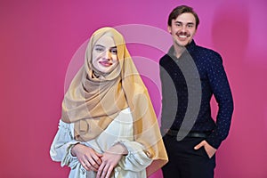 Portrait of happy young muslim couple standing isolated on pink background