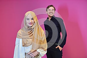Portrait of happy young muslim couple standing isolated on pink background
