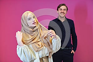 Portrait of happy young muslim couple standing isolated on pink background