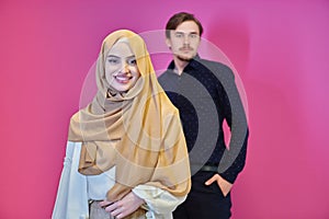 Portrait of happy young muslim couple standing isolated on pink background