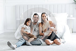 Portrait of happy young parents and their little children in the bedroom