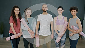 Portrait of happy young people man and women smiling in yoga studio holding mats