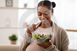 Portrait of happy young pregnant woman eating salad at home