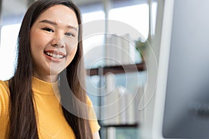 Portrait happy young programmer Asian woman work at start up technology office and using computer for coding application program