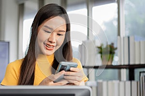 Portrait happy young programmer Asian woman work at start up technology office and using smartphone and testing mobile application