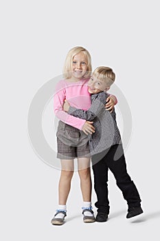 Portrait of happy young siblings hugging over white background