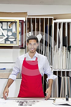 Portrait of a happy young skilled worker standing with meter stick in workshop photo