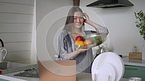 Portrait of happy young slim Asian woman with toothy smile posing in kitchen with healthful fruits and vegetables