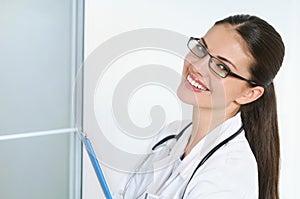 Portrait of happy young smiling female doctor with clipboard at office