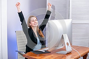 Portrait of happy young successful businesswoman celebrate something with arms up at office. Positive emotion. Big deal, promotion