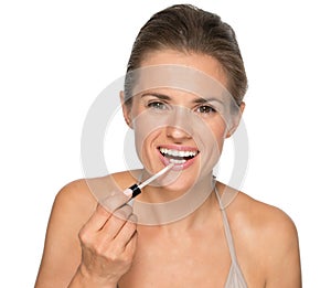 Portrait of happy young woman applying lip gloss