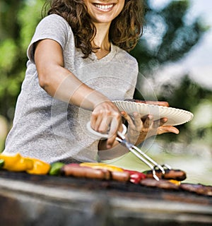 Portrait of happy young woman barbecuing at park